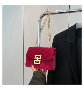 Détail du sac bandoulière en velours rouge avec texture matelassée et fermoir doré