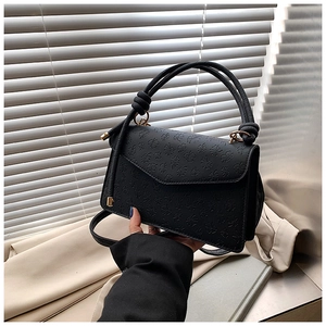 Détails du cuir gaufré à trèfles noirs et des ferrures dorées sur le sac à main