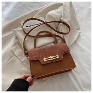 Close-up of brown textured leather crossbody bag with woven flap and gold geometric lock