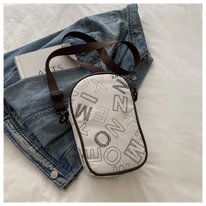 Detailed close-up of white crossbody bag with artistic black letter print and brown strap