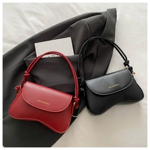 Detail of elegant black and red handbags featuring wave-shaped bottom and gold lettering