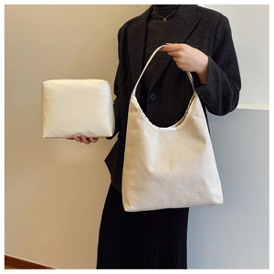 Detail view of beige canvas tote bag set with matching small zipper pouch held by model