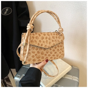 Détail du sac à main beige avec imprimé floral marron et poignée à nœud unique