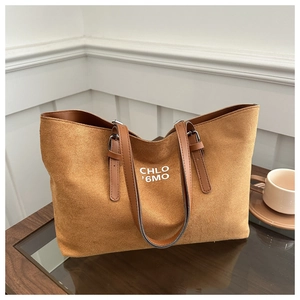 Detail of adjustable brown leather strap and silver buckle on caramel suede tote bag