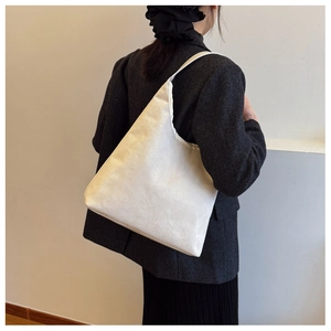 Street style shot of a cream high-capacity canvas hobo bag worn with a blazer suit