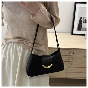Minimalist black baguette shoulder bag with gold crescent buckle styled on a model
