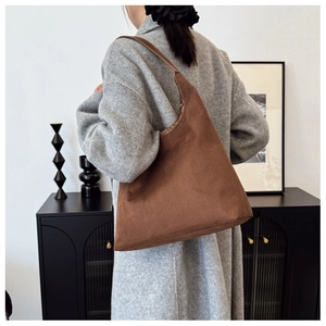 Detail of caramel brown suede hobo bag with seamless strap on shoulder of a model