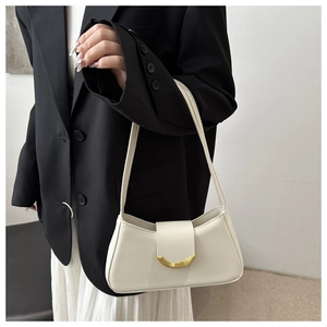 Detail of cream minimalist underarm bag with gold crescent buckle on black blazer background