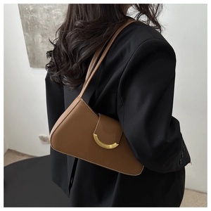 Detailed side view of brown leather baguette bag with crescent gold buckle on shoulder
