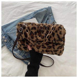 Detail of leopard print faux fur handbag with thick acrylic chain and denim background