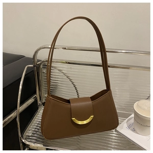 Close-up of a brown leather shoulder bag with a gold crescent metal buckle on a chair