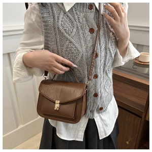 Detail of vintage dark brown crossbody bag with metal buckle and soft leather texture