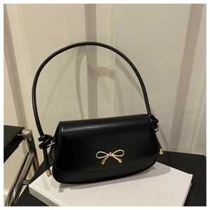 Detailed shot of a black matte leather handbag featuring a golden metal bow buckle