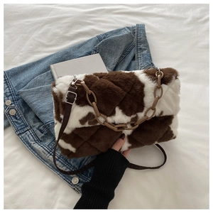 Detail of plush cow print crossbody bag with brown resin chain and adjustable leather strap
