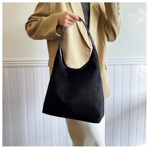 Detail view of black large suede hobo bag carried by a model in casual attire