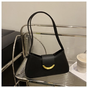 Close-up of black matte leather shoulder bag with gold crescent buckle on a display stand