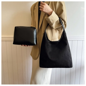 Detailed view of black minimalist tote bag and pouch set styled on elegant office outfit