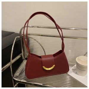 Close-up of vintage burgundy crescent shoulder bag with elegant gold horseshoe buckle