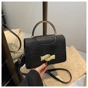 Detail of crocodile embossed leather texture with wavy gold metal buckle on crossbody bag