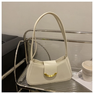 Close-up of cream shoulder bag with smooth leather and a gold magnetic buckle