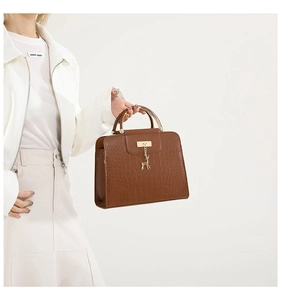 Détail du sac à main marron effet croco avec poignée dorée et pendentif cerf
