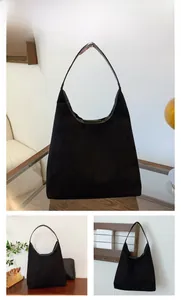 Detail view of a black suede Hobo tote bag with slender leather shoulder straps
