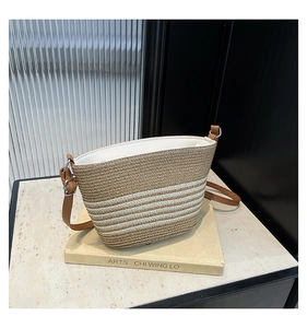 Détail du sac seau rayé en paille avec bandoulière en cuir brun et texture tressée fine