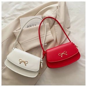 Close-up of white and red PU leather handbags with golden bow metal buckle detail