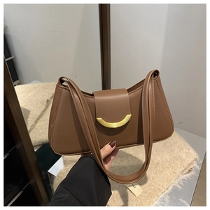 Detail of a brown leather baguette bag featuring a gold half-moon magnetic clasp and strap