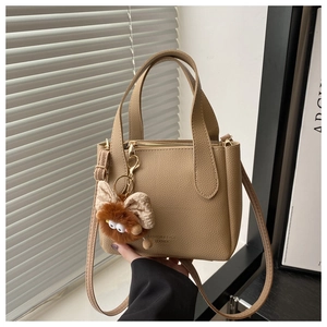 Detail of khaki lychee grain leather bucket bag with cute plush monster charm