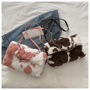 Detail of plush cow print shoulder bags with quilted pattern and chain decoration