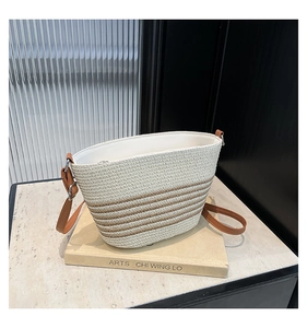 Détail du sac seau en paille rayé avec bandoulière en cuir marron réglable et doublure