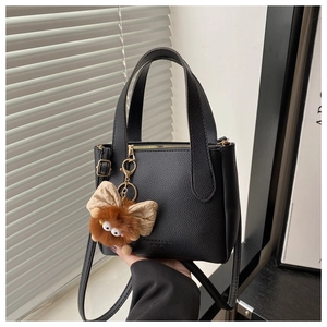 Detail of black lychee grain leather bucket bag with plush charm and fashion embossing