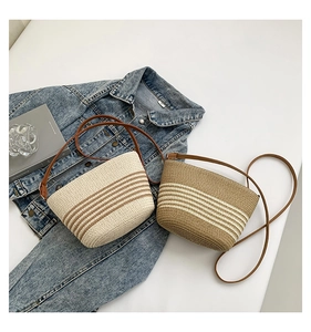 Flat lay of striped straw bucket bags with brown leather straps and denim jacket