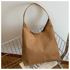 Detail of a large brown suede tote bag featuring faux leather straps inside a shopping cart