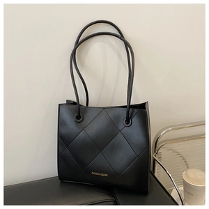 Dettaglio della borsa tote trapuntata nera con scritte dorate su una superficie elegante