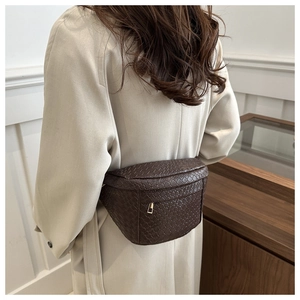 Detailed view of dark brown woven leather texture and gold zipper on a waist bag