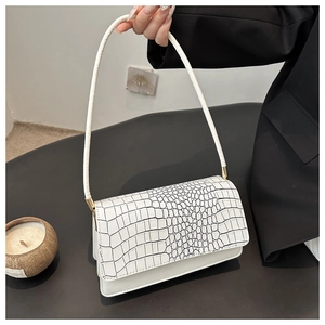 Close-up of white crocodile pattern flap and gold hardware on minimalist underarm bag