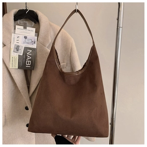 Detail of dark brown suede tote bag with leather straps and pleated side structure