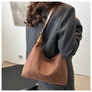 Detail view of large brown suede hobo bag styled with a professional grey blazer suit