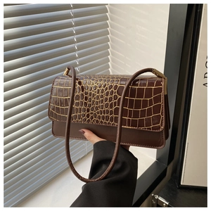 Detailed view of dark brown faux crocodile leather texture and golden metal buckle on bag