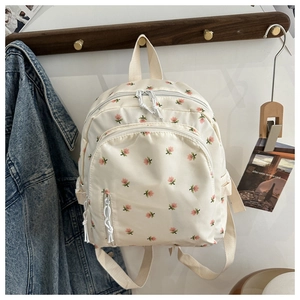 Detail of floral mini backpack in cream featuring front zipper pocket and woven handle