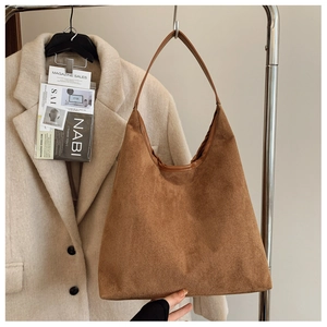 Detail of a brown suede hobo bag with a minimalist wide strap on a steel hanger