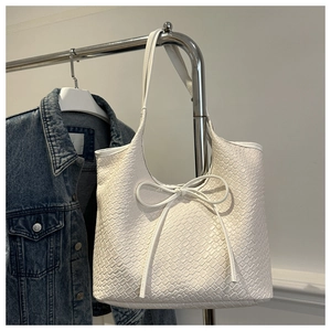 Detailed texture of white woven tote bag with a decorative bow on a metal hanger