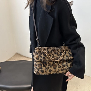 Fuzzy leopard print crossbody bag with chunky chain strap worn by model in black coat