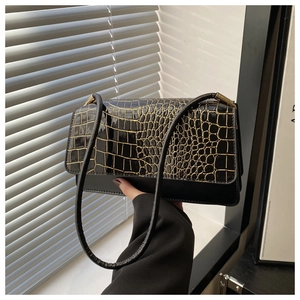 Close-up of black crocodile texture flap with gold trim on a vintage shoulder bag