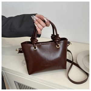 Close-up of a dark brown matte leather bucket bag with embossed Fashion logo detail