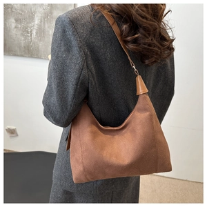 Deep brown suede hobo bag on model's shoulder showing soft half-moon silhouette