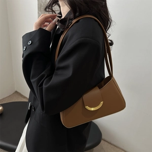 Vintage brown leather shoulder bag with gold crescent buckle shown on a model