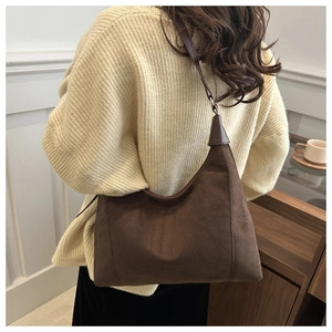 Detail of dark brown suede hobo bag shown on shoulder with minimalist retro design